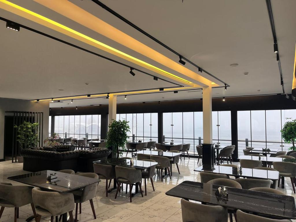 um restaurante com mesas, cadeiras e janelas em Jupiter em Baku