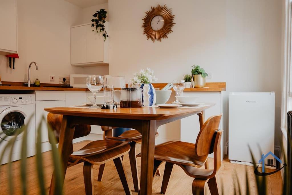 a kitchen with a wooden table and chairs with wine glasses at Contemporary flat, sleeps 4, very central, parking in Northampton