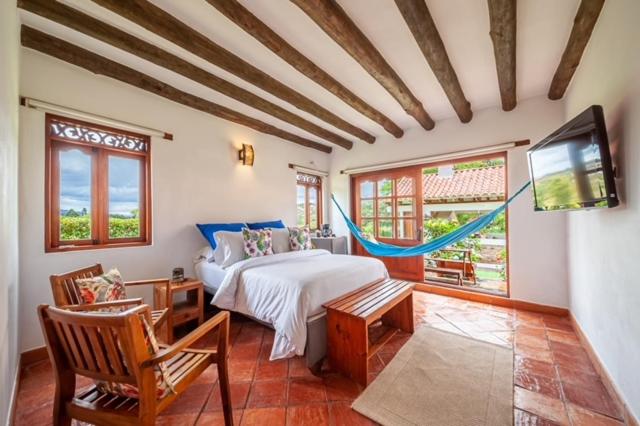 um quarto com uma cama e uma televisão de ecrã plano em Casa de las Flores em Villa de Leyva