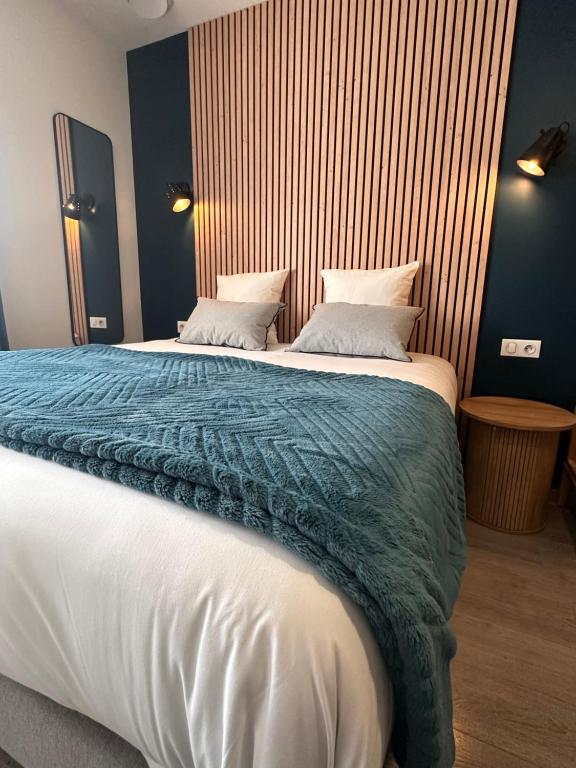 - une chambre avec un grand lit et une couverture bleue dans l'établissement Auberge du Vieux Lanas Logis Hotel Restaurant, à Lanas