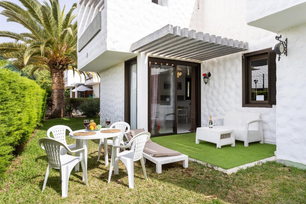 a patio with a table and chairs on a green lawn at Nice apartment in the heart of Las Americas in Playa de las Americas