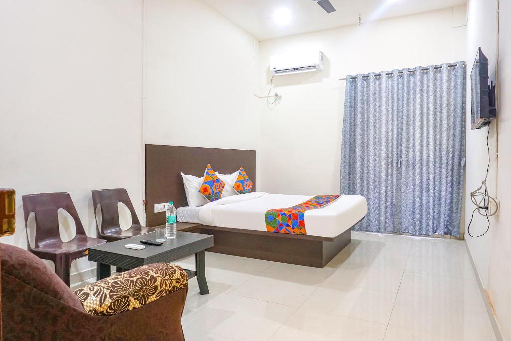 a bedroom with a bed and a chair and a table at FabHotel Om Sai in Nashik