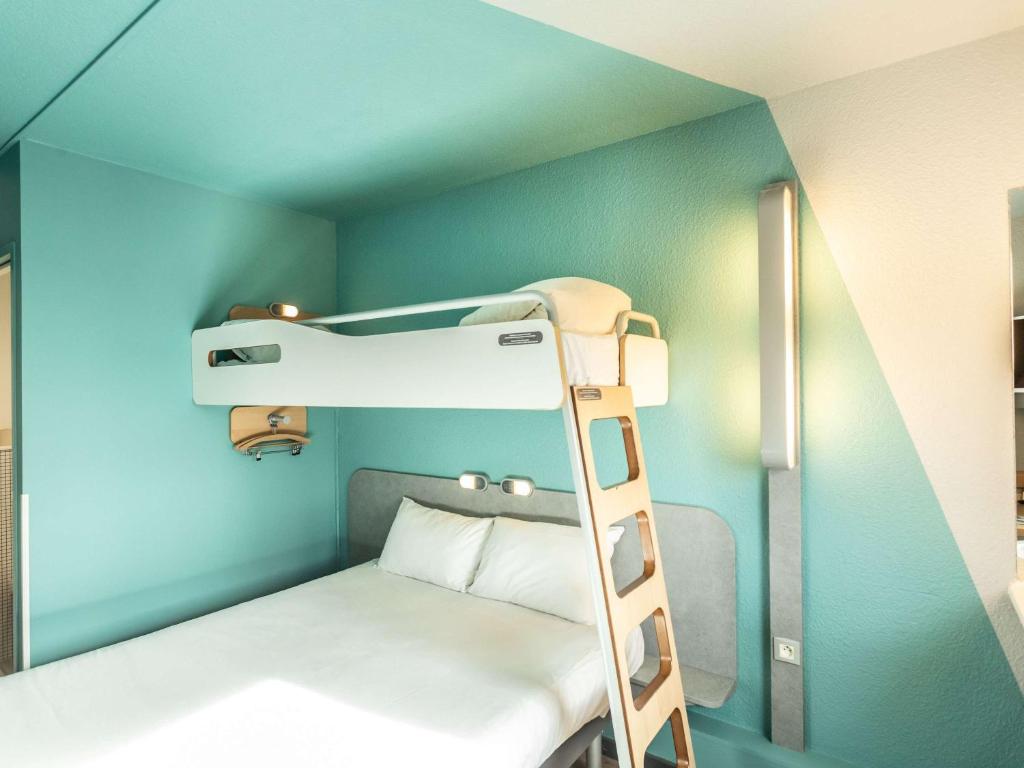 Ce lit superposé se trouve dans un dortoir avec une échelle. dans l'établissement ibis budget Bourges, à Bourges