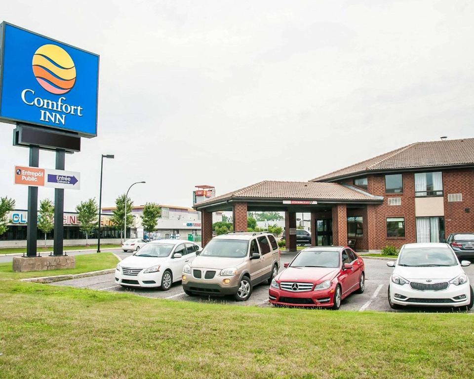 un gruppo di auto parcheggiate in un parcheggio di fronte a un hotel di Comfort Inn Laval a Laval