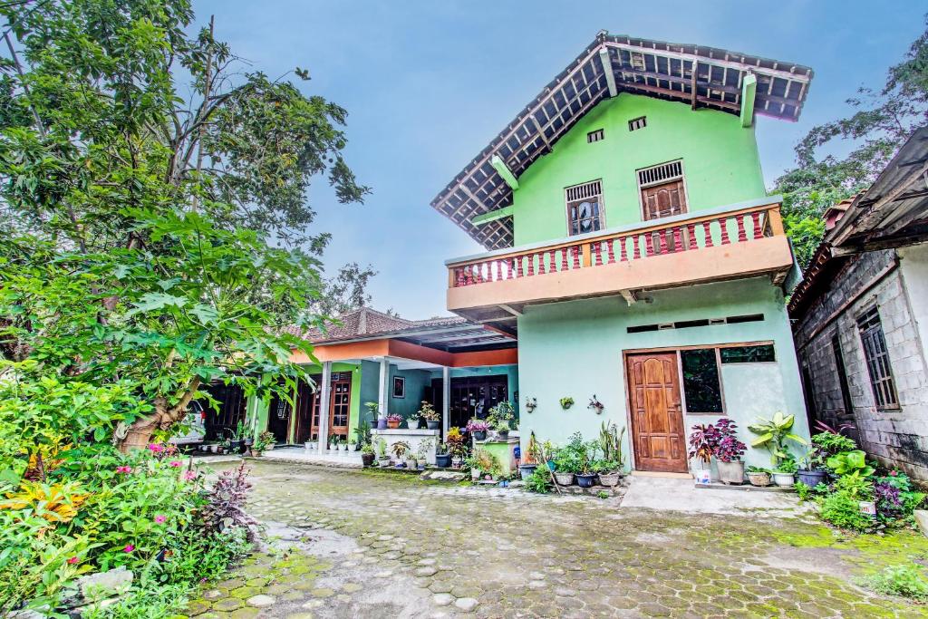 ein grünes Haus mit Balkon darüber in der Unterkunft SPOT ON 93592 Pondok Backpackers Ardafa Jogja in Manisrenggo