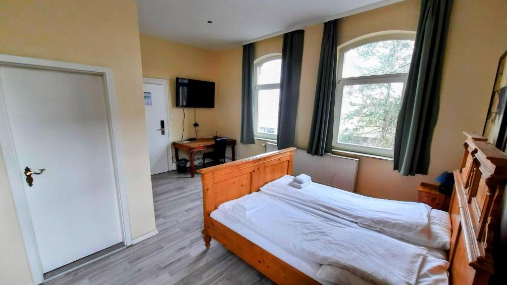 a bedroom with a bed and two windows and a door at Am Lindenhof - Self Check-In Hotel in Hannover