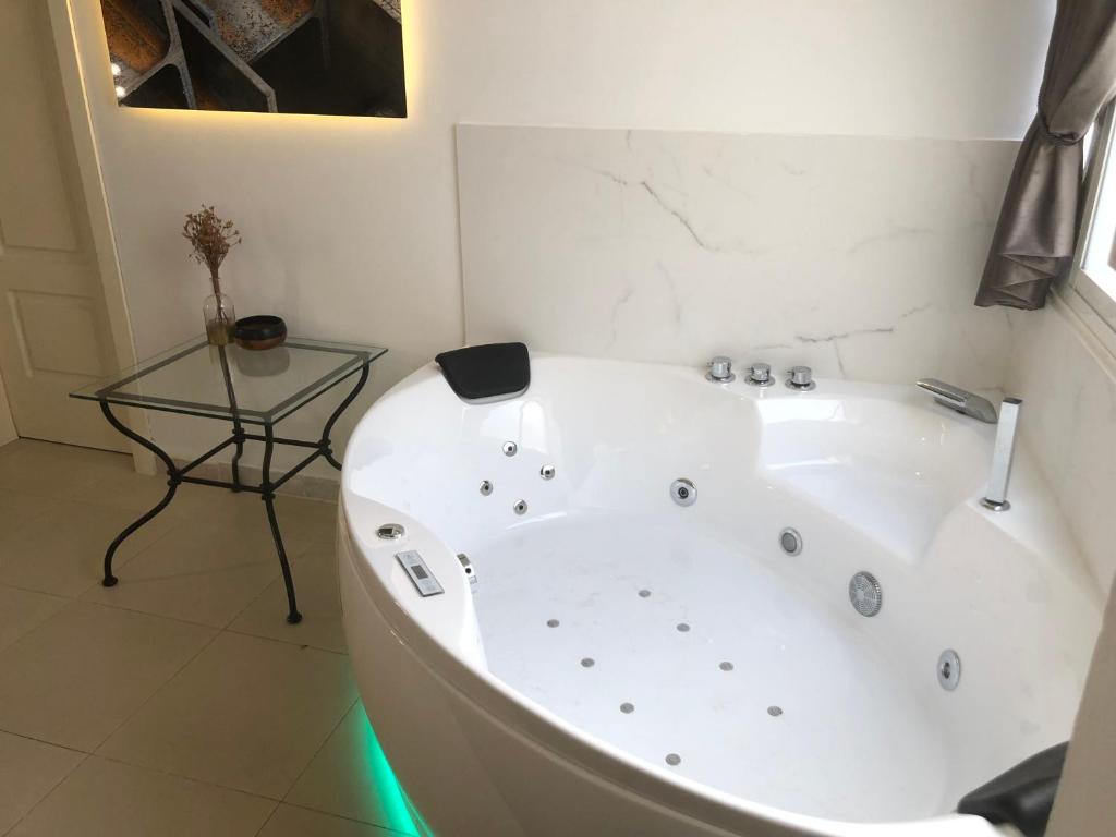 a white bath tub in a bathroom with a glass table at Apartamentos Las Naranjas in Jerez de la Frontera