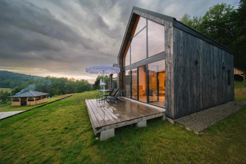 a house on a hill with a bench and an umbrella at Dolina Gwiazd in Ropienka