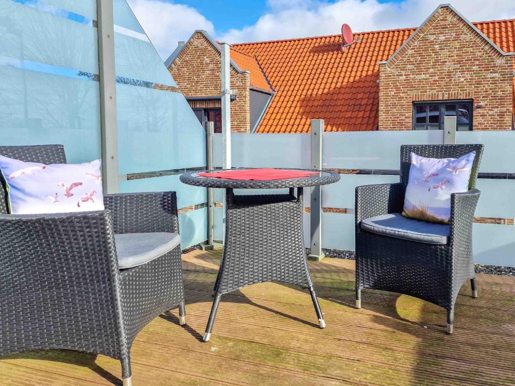 a patio with a table and chairs on a balcony at Sonnendeck in Greetsiel