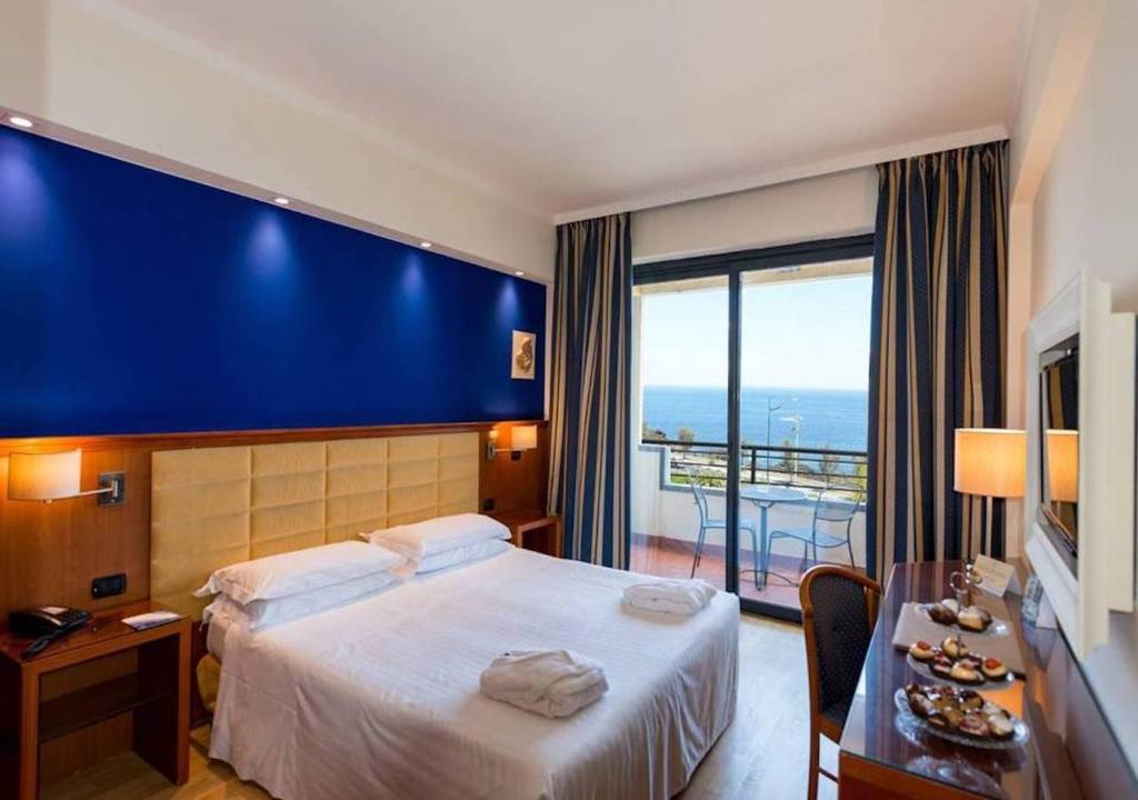 ein Hotelzimmer mit einem Bett und einem großen Fenster in der Unterkunft Hotel Nettuno in Catania
