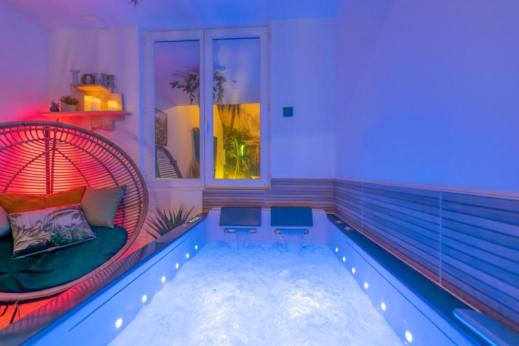 a room with a swimming pool with a wicker chair and an indoor swimming pool at Le temps d'un rêve - Escapade romantique in Abbeville