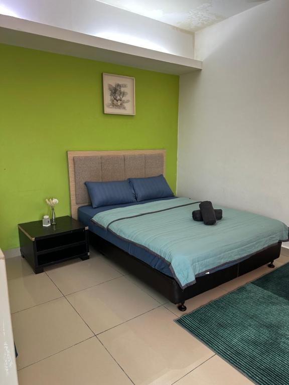 a bedroom with a bed and a green wall at De Vianna Apartment Wakaf Che Yeh in Kota Bharu