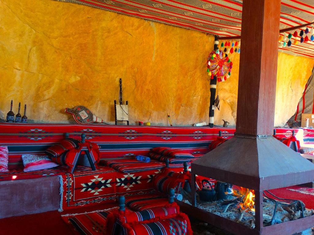 Wadi rum view camp في وادي رم: غرفة بها بطانيات حمراء وزرقاء ومدفأة