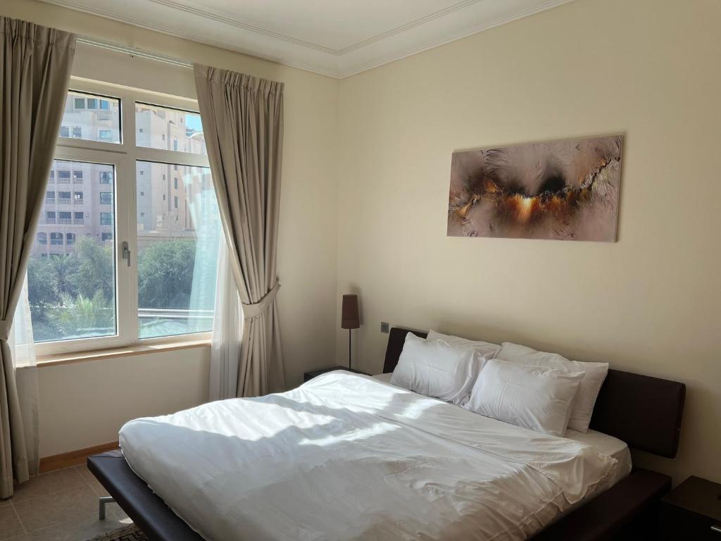 a bedroom with a white bed and a window at Palm Jumeirah - Dubai 3 Bedroom Park Side - With Beach Access in Dubai