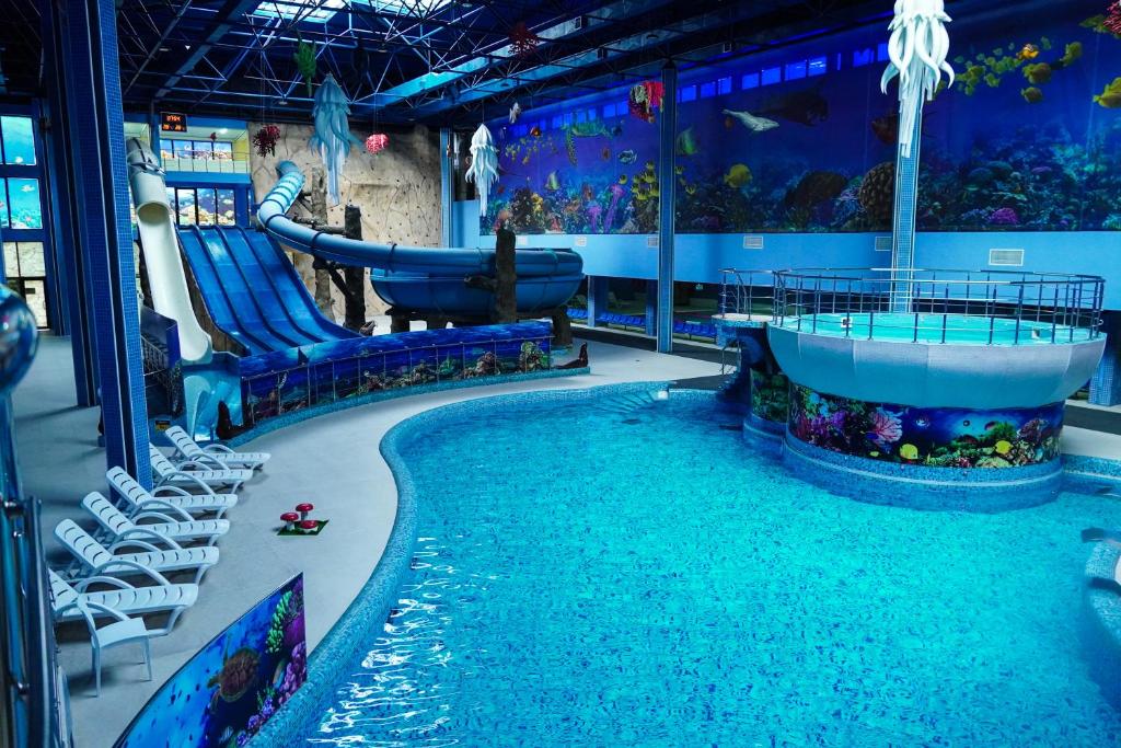 an indoor water park with a slide and an aquarium at Aquapark Hotel & Villas in Yerevan