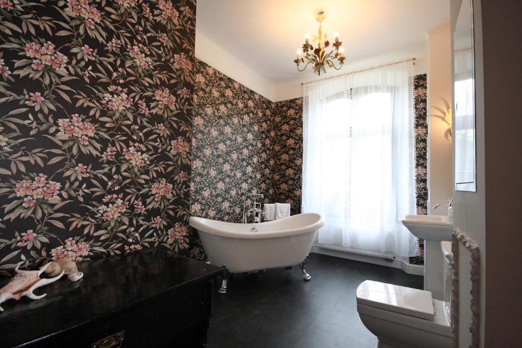 La salle de bains est pourvue d'une baignoire et de papier peint floral. dans l'établissement Suite Georg Anno 1869 HERRENHAUS VIECHELN, à Behren-Lübchin