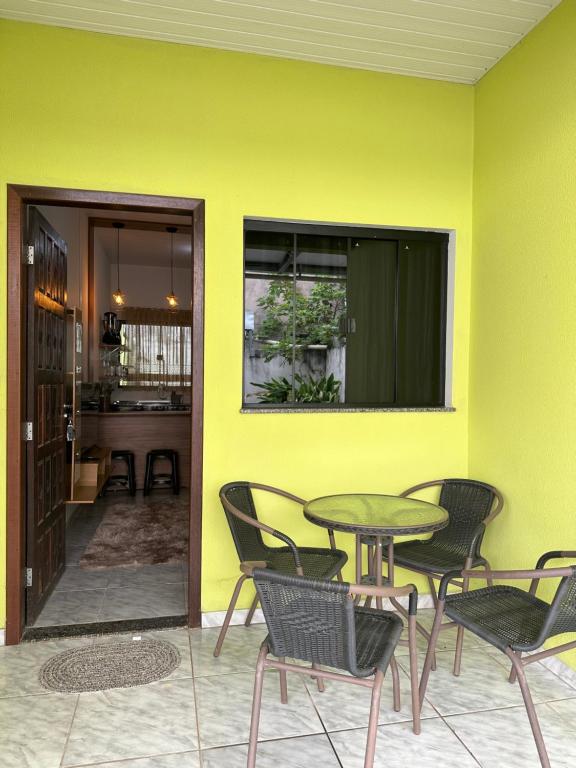 a table and chairs in a room with a yellow wall at Apart Aconchego Mobiliado Centro in Sinop