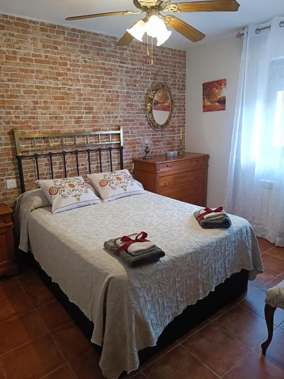 a bedroom with a large bed and a brick wall at PINAR DE LAS CABAÑUELAS in Villanueva de Duero