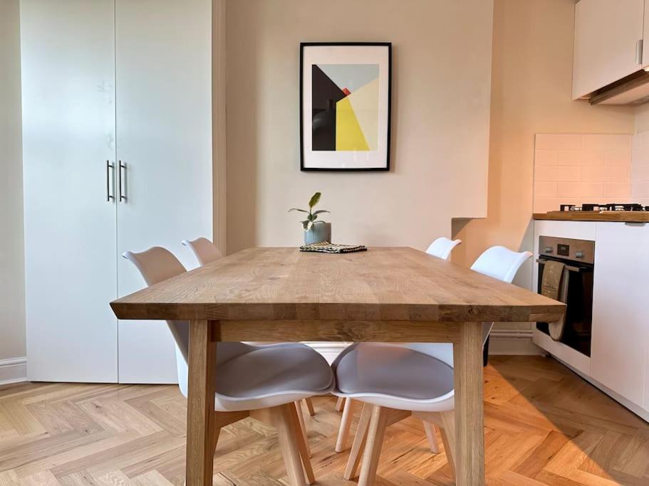 uma mesa de jantar com cadeiras brancas numa cozinha em Designer 2 bedroom flat with office em Londres