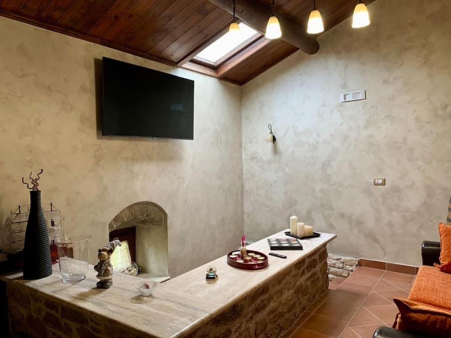 uma sala de estar com lareira e uma televisão na parede em Il Casale - tra Passato e Modernità 