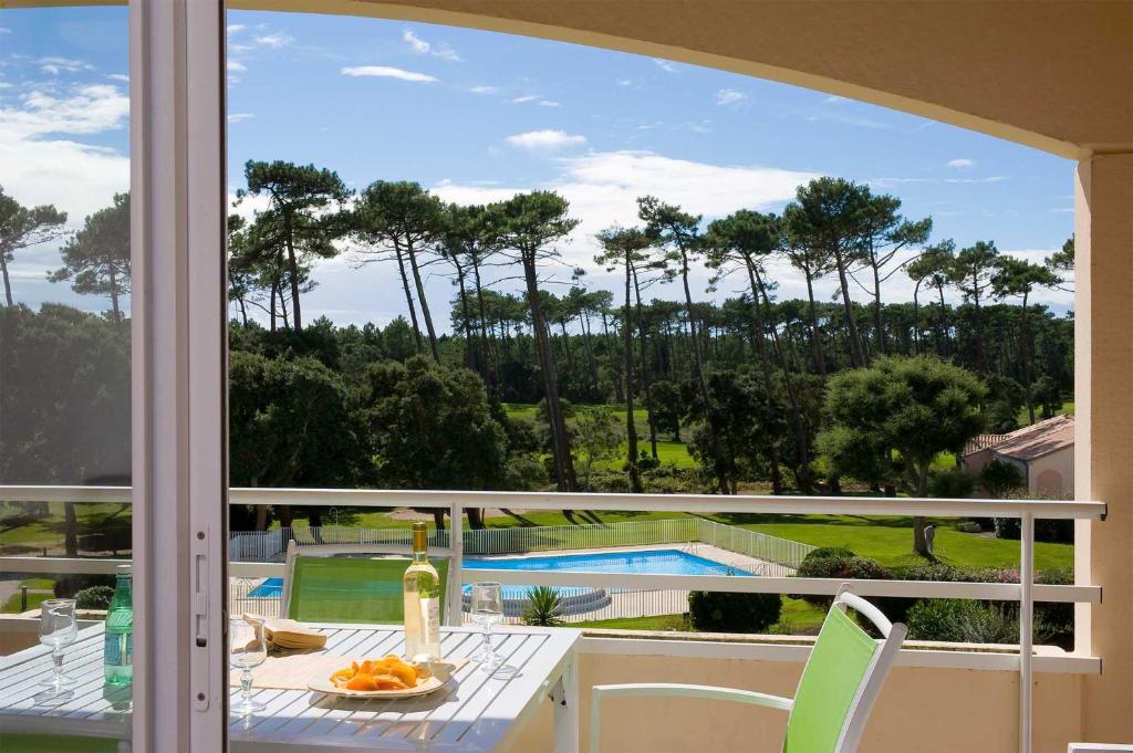 d'un balcon avec une table et une vue sur la piscine. dans l'établissement Madame Vacances Les Appartements de Moliets, à Moliets-et-Maa