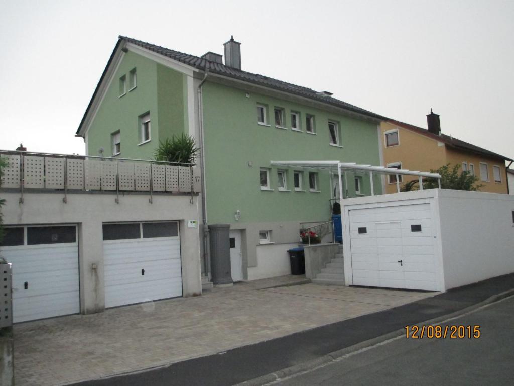 ein grünes Haus mit zwei Garagen und einer weißen Garage in der Unterkunft Ferienwohnung Hein in Iphofen