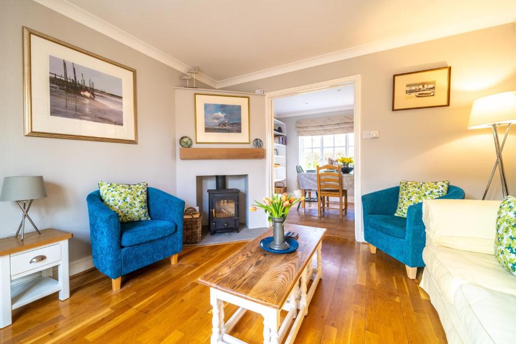 a living room with blue chairs and a fireplace at Mahonia Cottage in Burnham Market