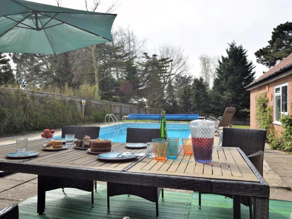 a wooden table with food and an umbrella on a patio at 5 Bed in Woodbridge 72724 in Woodbridge