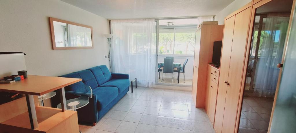 un salon avec un canapé bleu et une table dans l'établissement Studio calme à 50m de la plage et petite vue mer, au Grau-du-Roi