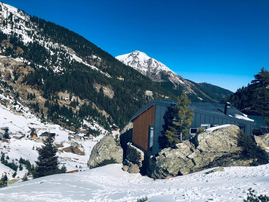 a building in the snow with a mountain in the background at Cabin on a Rock - Mountain Escape in Deçan