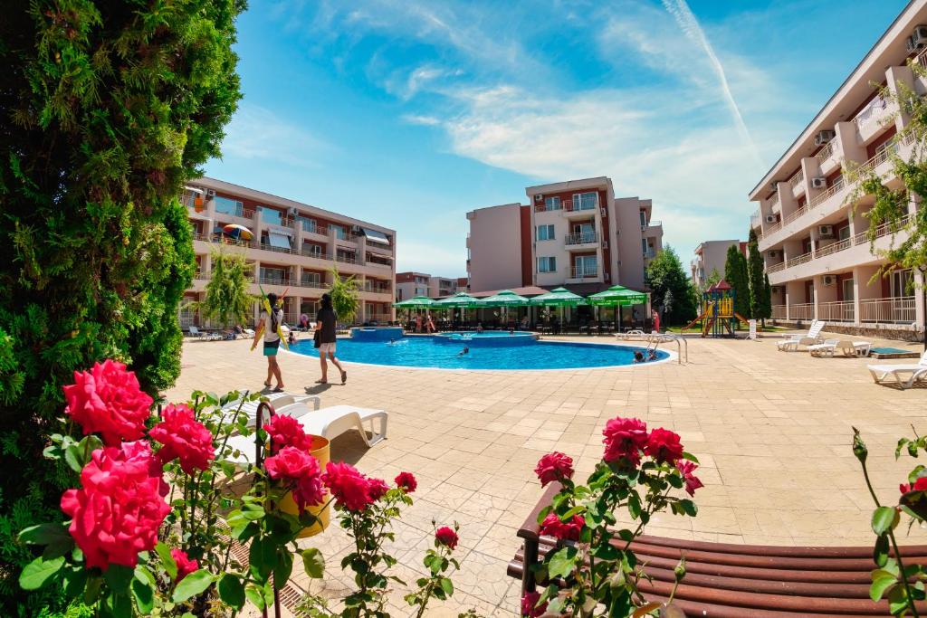 un patio con piscina y rosas rojas en Nessebar Fort Club Apartments, en Sunny Beach