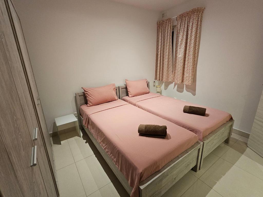 um quarto com 2 camas com lençóis cor-de-rosa e uma janela em Luxury Waterfront Apartment em Mellieħa