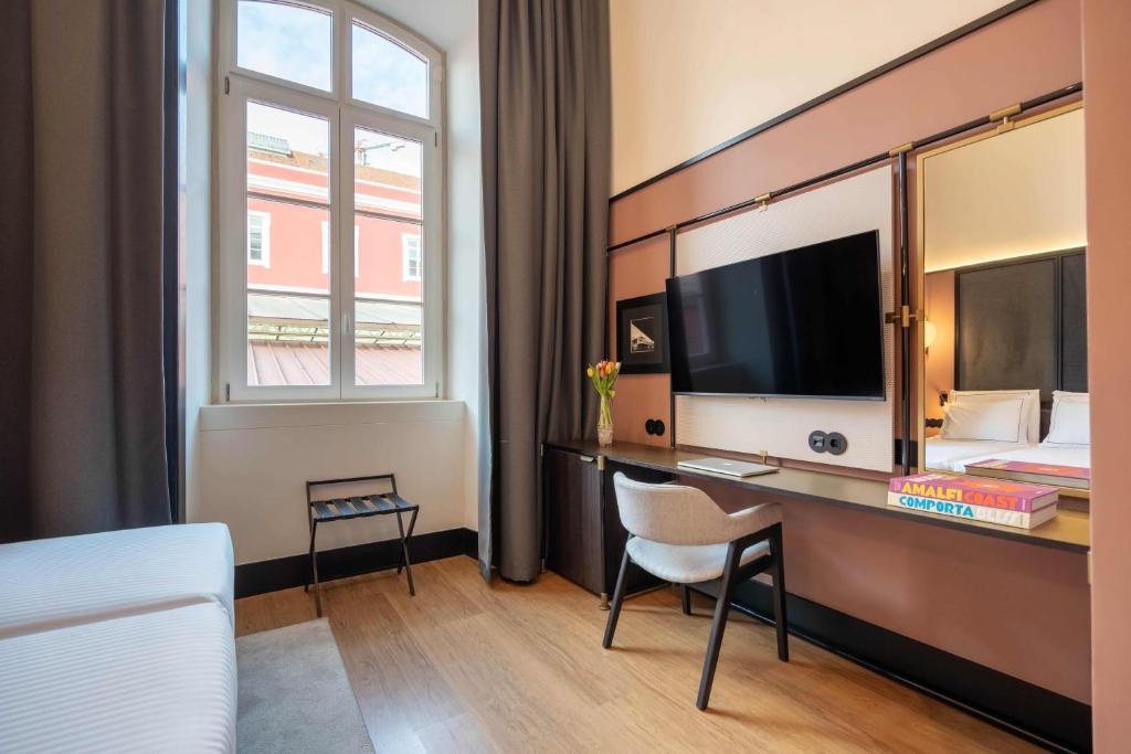 A built-in desk and television beside the room's tall window.