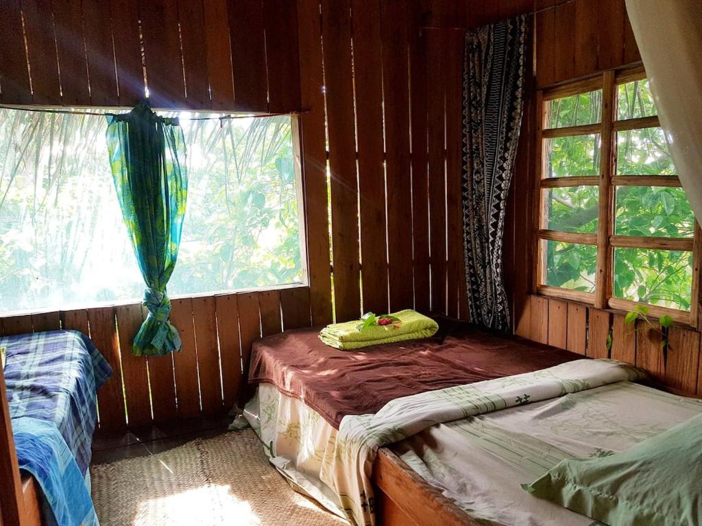 a room with two beds in a wooden cabin at Tanna Eagle twin volcano view tree house in White Sands