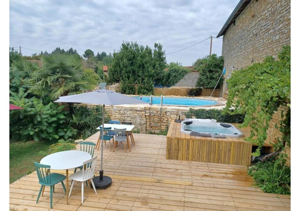 eine Terrasse mit Tischen, einem Sonnenschirm und einem Pool in der Unterkunft Nid Charentais Angouleme pool jacuzzi in La Poterie