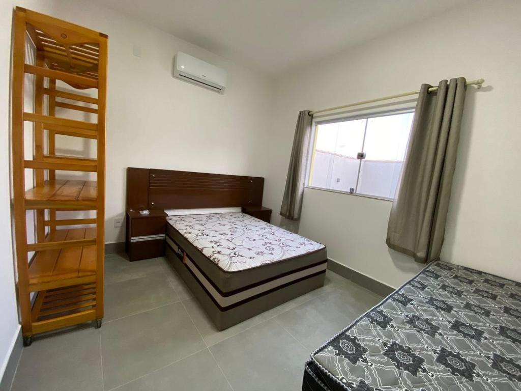 1 dormitorio con 2 camas y ventana en Casas Amarelas II - Prado BA en Guarani