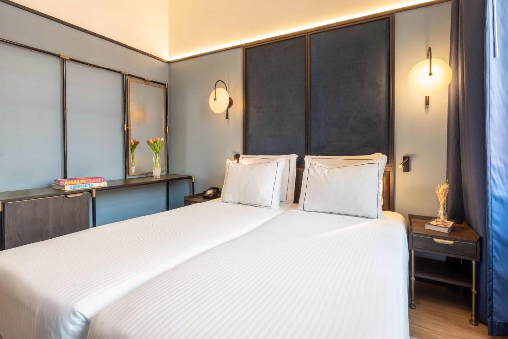 A twin bedroom framed around two white beds and a long mirrored dressing console.