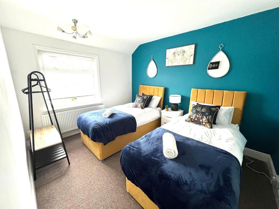 1 dormitorio con 2 camas y pared azul en Holborn en Coundon