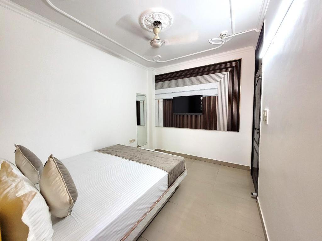 a white bedroom with a bed and a television at HOTEL ANCHAL DX in New Delhi