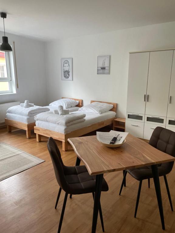 Cette chambre comprend deux lits, une table et des chaises. dans l'établissement Appartement Donauwelle 2, à Passau