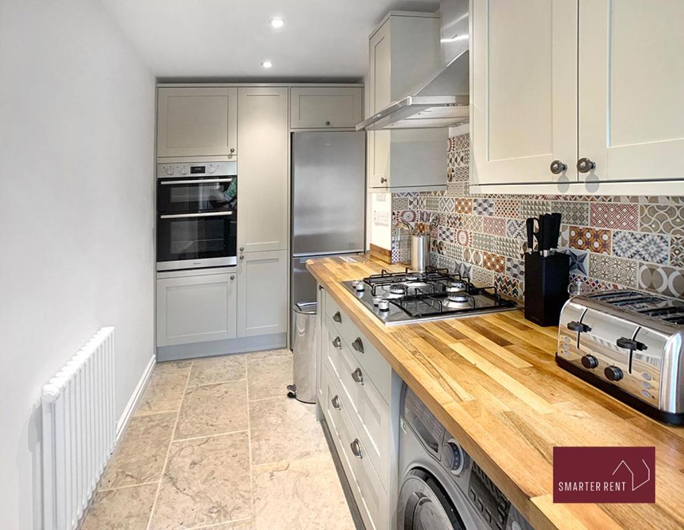 eine Küche mit weißen Schränken und einem Herd mit Backofen in der Unterkunft Farnborough - Newly Refurbished 2 Bedroom Home in Blackwater