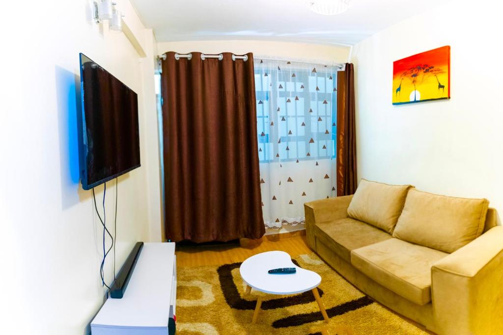 ein Wohnzimmer mit einem Sofa und einem TV in der Unterkunft Havana Apartments-South B in Nairobi