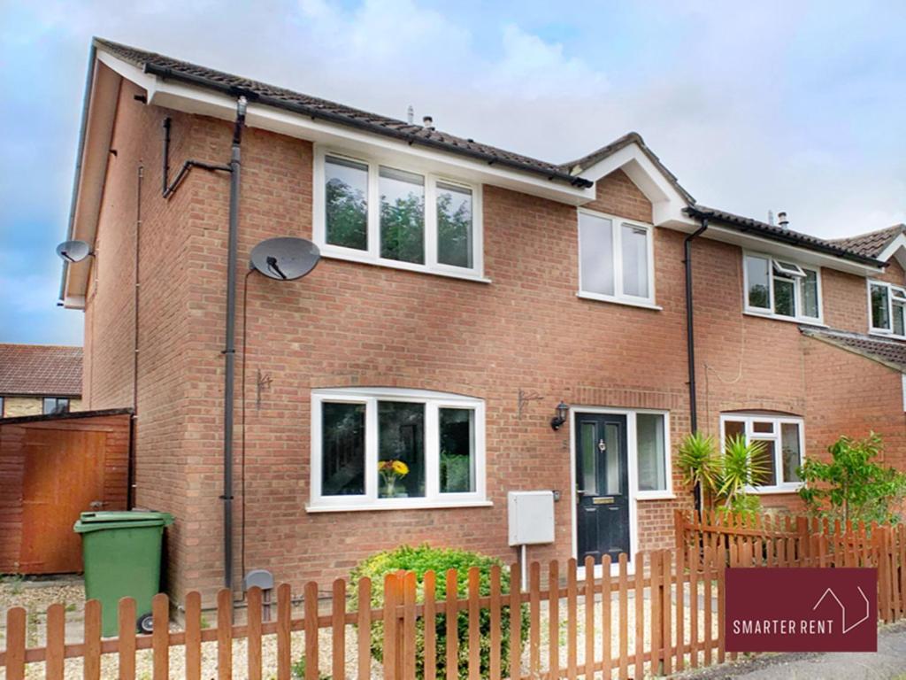 a brick house with a fence in front of it at Bisley - 2 Bedroom House - Front Garden and Parking in Bisley