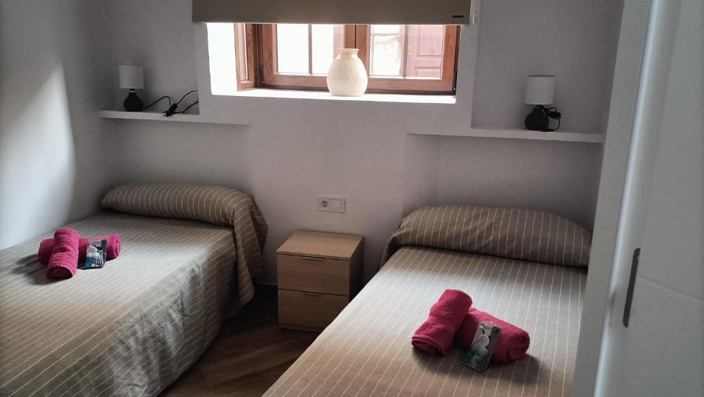 two beds in a small room with pink pillows at APARTAMENTOS BAHÍA SUR CADIZ LUZ DE LA BAHÍA San Fernando in San Fernando