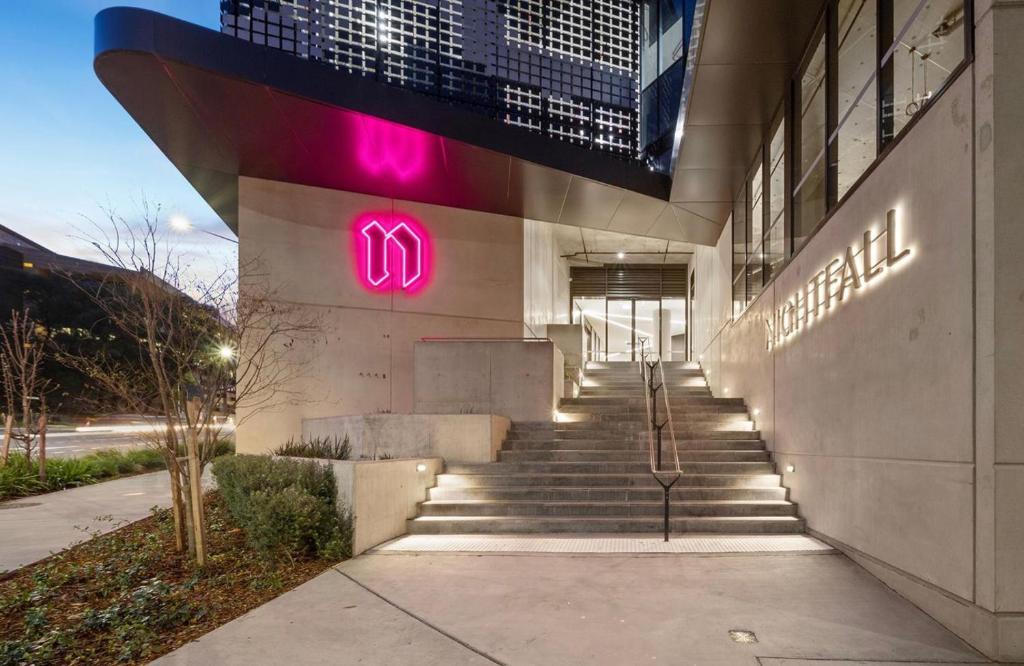 a building with pink neon signs on the side of it at 2 Bedroom Apartment on Nightfall in Belconnen