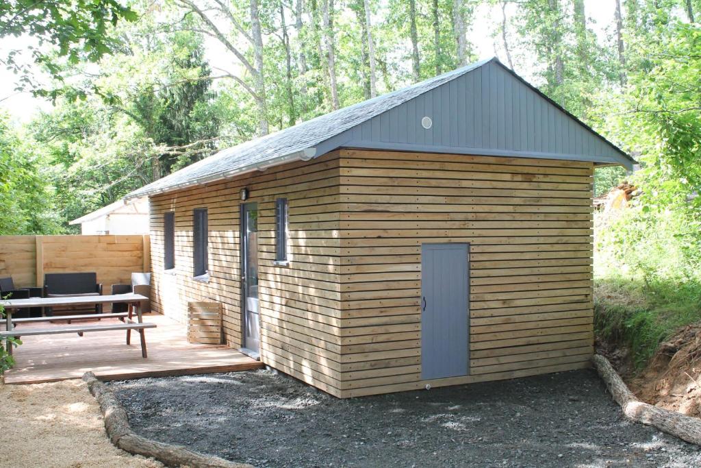 einem Holzschuppen mit einem Picknicktisch und einer Bank in der Unterkunft Camping Moulin De La Geneste in Condat-sur-Ganaveix