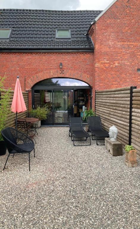 un patio avec des chaises et une table et un bâtiment dans l'établissement Gîte ELIROSE, à Rosult