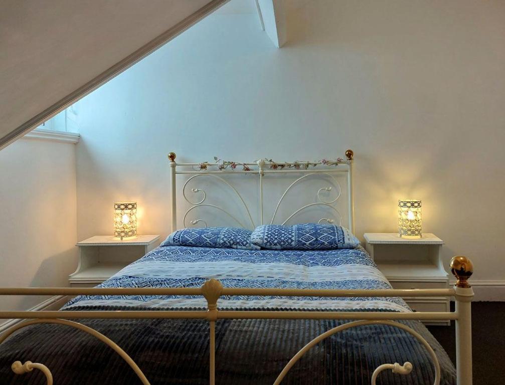 a bed in a bedroom with two lamps on the sides at Trem Y Mor - Edge of the Sea in Tywyn