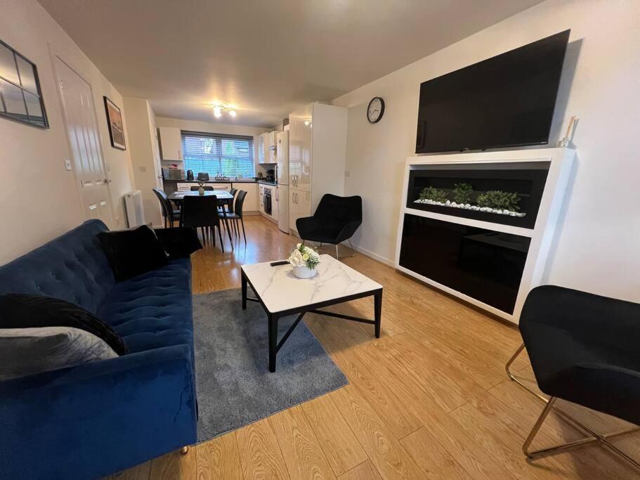 a living room with a blue couch and a fireplace at Braid House in Loughborough