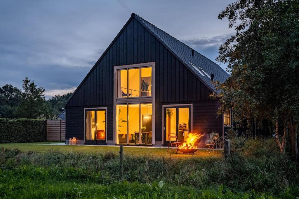 uma casa negra com uma lareira à frente. em Het Landzicht 
